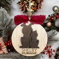Wooden ornament with cat and dog silhouette and 'Shelby Humane' text, surrounded by Christmas decorations.