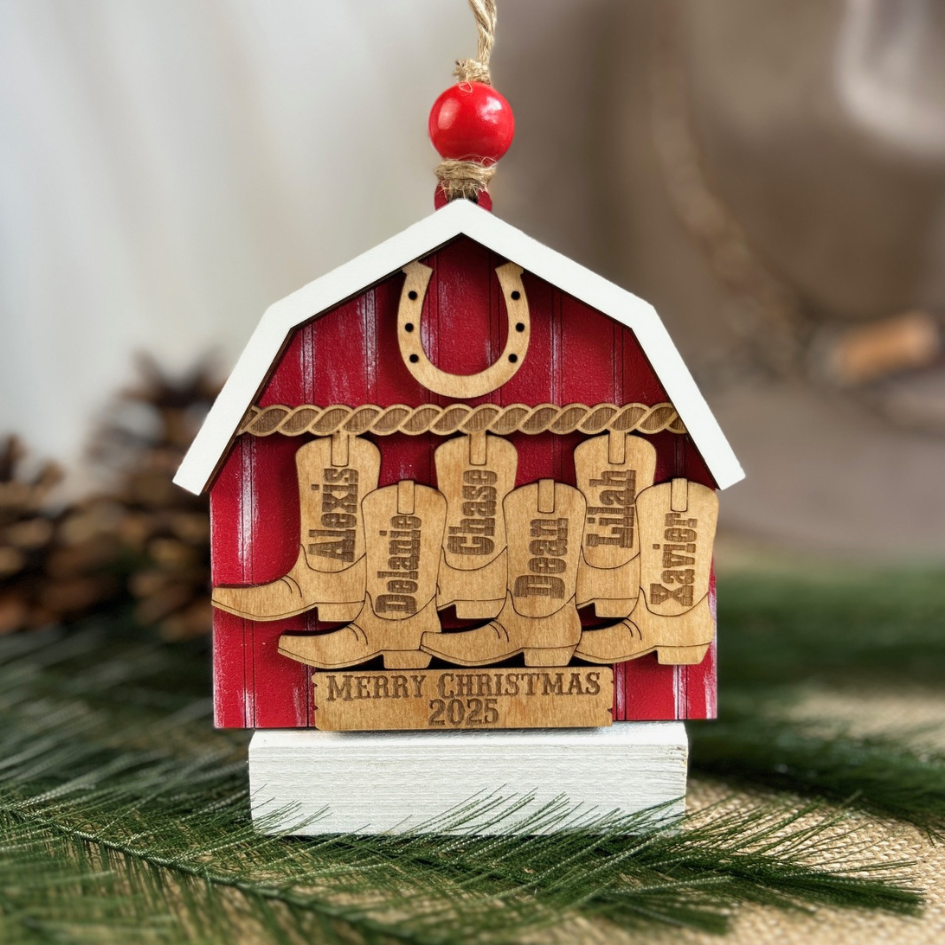 Decorative Christmas ornament shaped like a barn with horse shoes and personalized names on a green background.