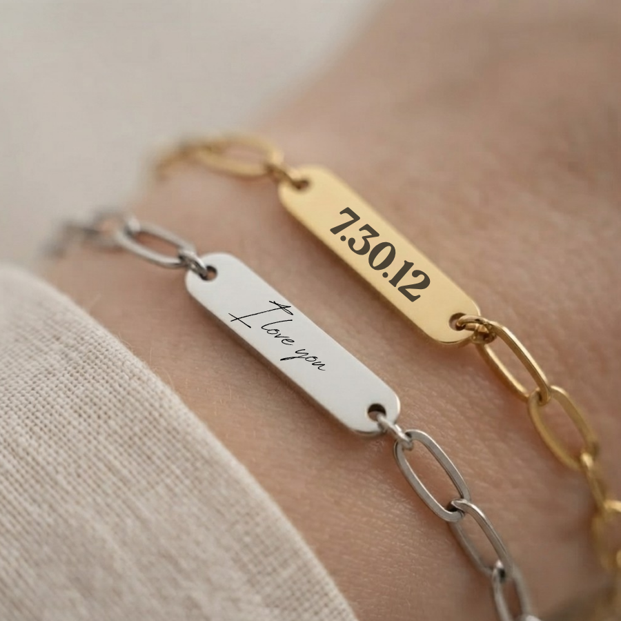 Two personalized bracelets on a wrist, one in silver with an engraved 'I love you' tag and chain, and one in gold with an engraved date '7.30.12'.