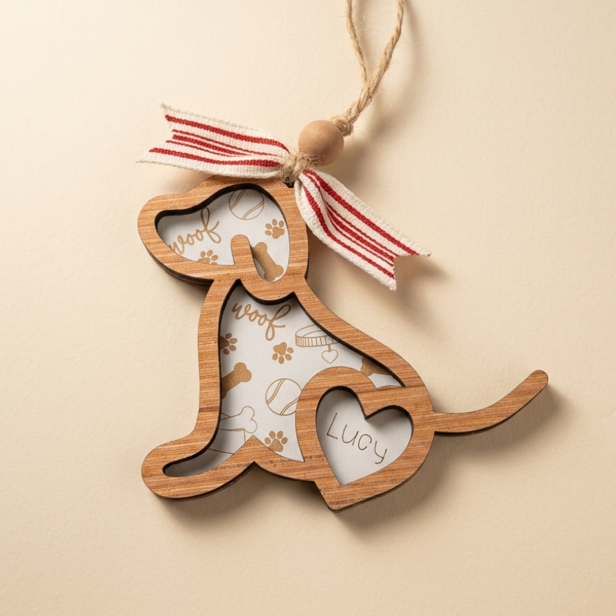 A wooden dog-shaped hanging ornament with a natural wood finish, featuring cutout sections with a white insert printed with dog-themed doodles and the name 'Luoy'. It is decorated with a red and white striped ribbon and a wooden bead loop at the top, shown on a plain beige background.